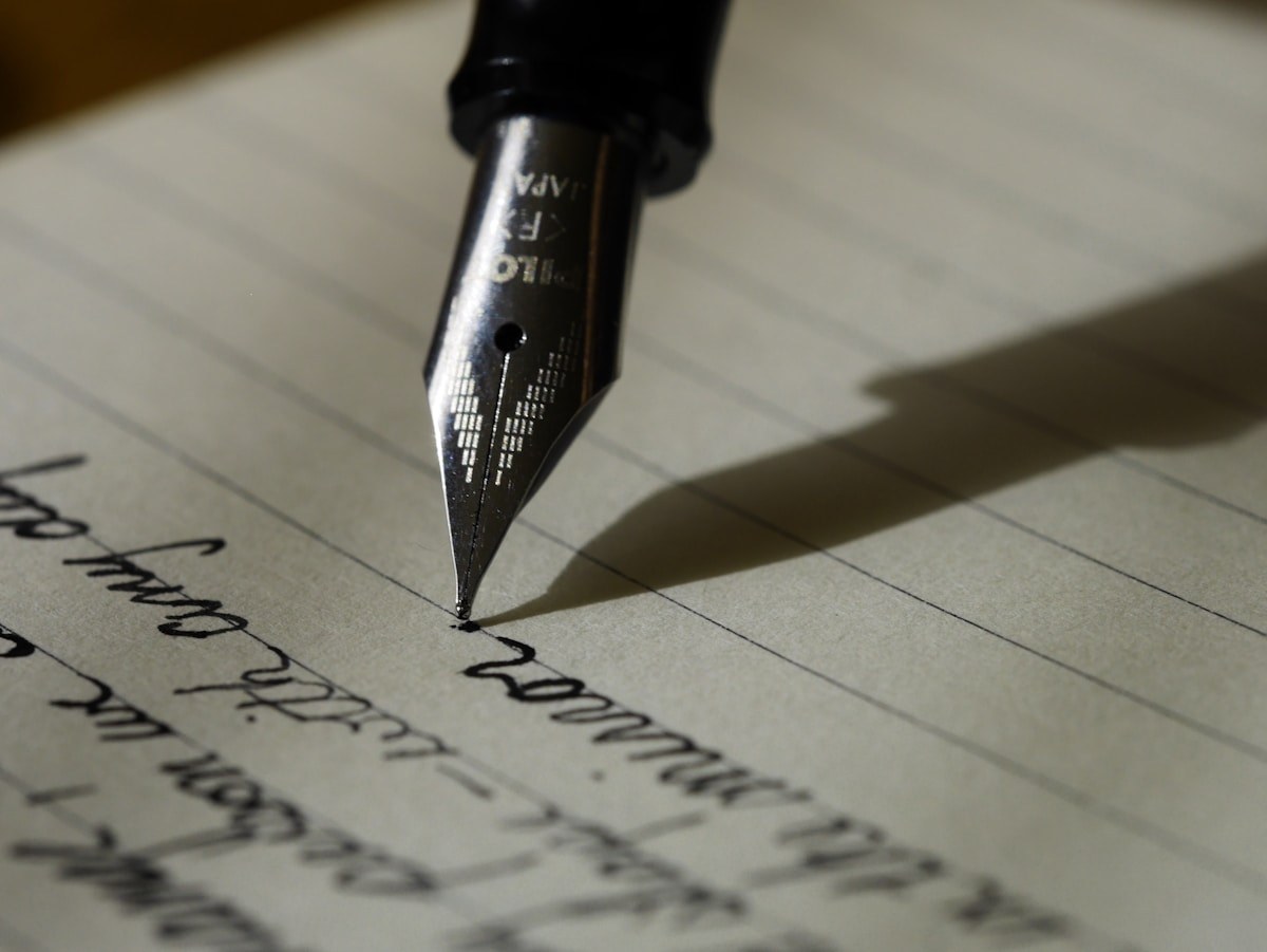 An open notebook on a desk, margin line visible, pages filled with handwriting